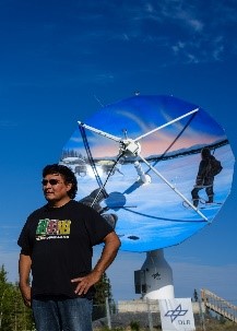 Gwich'in Artist, Ronnie Simon, in front of the DLR (German Aerospace Centre) antenna